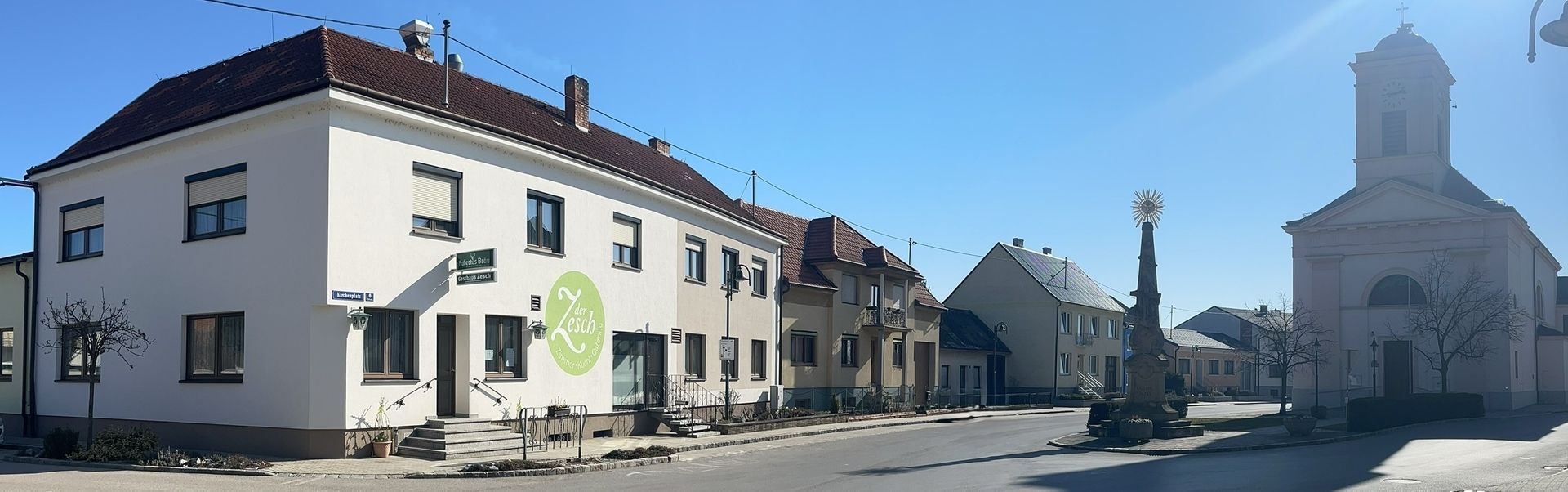 Straßenszene mit bunten Wohnhäusern und einer rosa Kirche in einem kleinen Ort bei Tageslicht